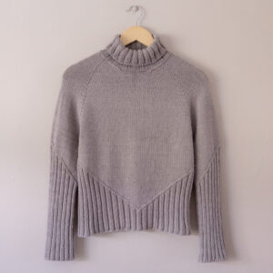 Grey handknit Fall Line sweater on a hanger